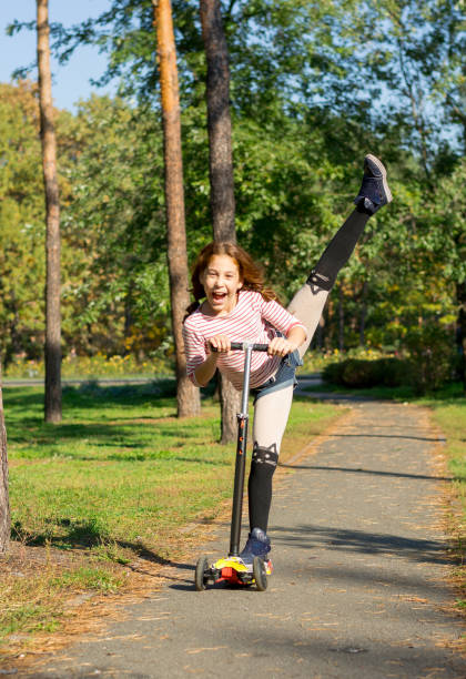 istock The girl goes on a scooter, performing acrobatic exercises 868405192