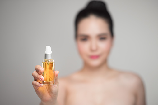 Beauty concept. Asian pretty woman with perfect skin holding oil bottle