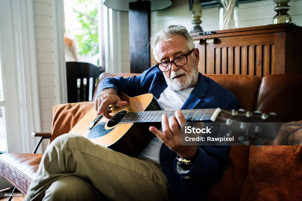 An elderly man is playing guitar Senior Adult Stock Photo