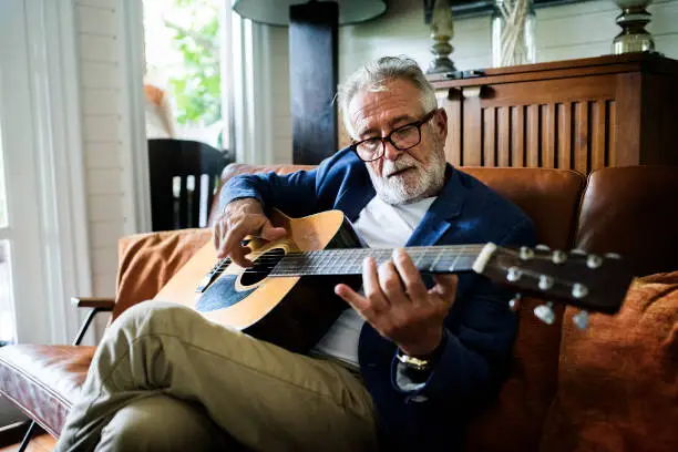 Photo of An elderly man is playing guitar