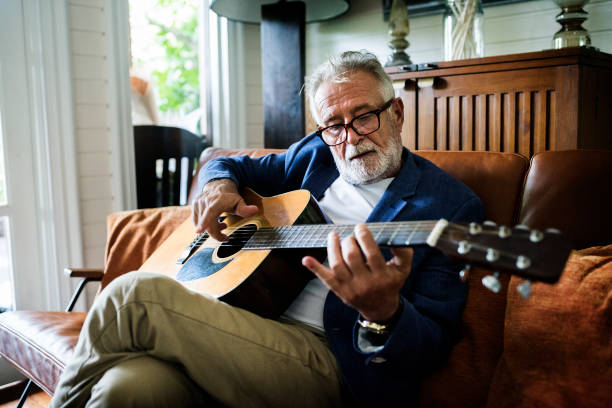 an elderly man is playing guitar - hobbies imagens e fotografias de stock