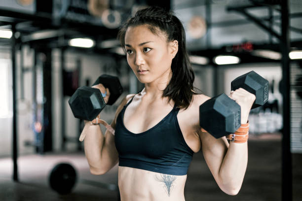 istock Beautiful Asian woman doing Dumbbell Bicep Curls 868424964