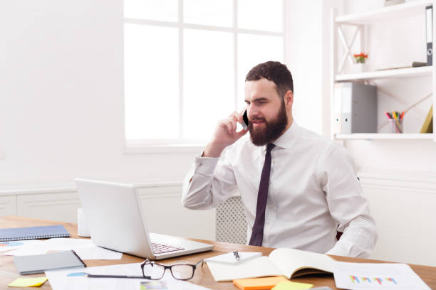 istock Young serious businessman with laptop in modern white office 868428980