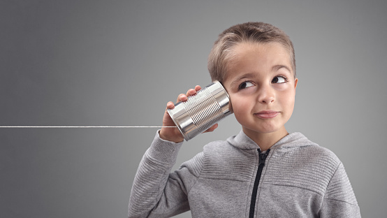 Boy on tin can phone listening to curious good news