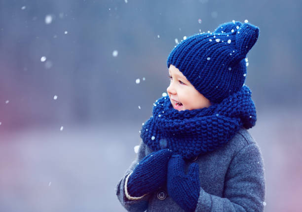 istock cute kid, boy in winter clothes playing under the snow 868436564