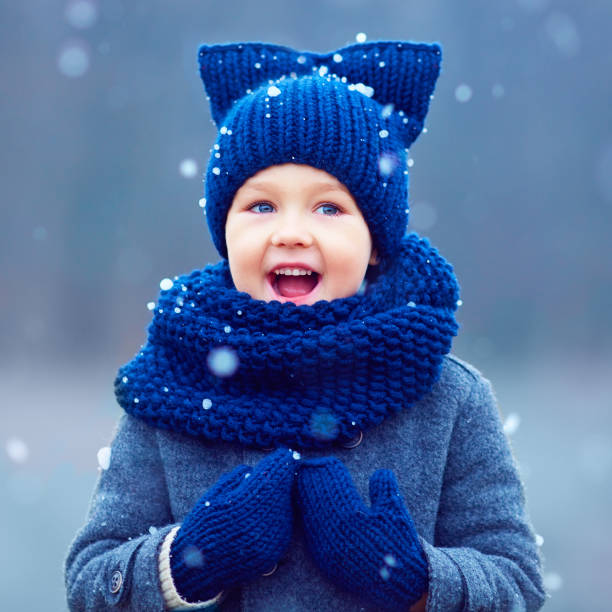 istock cute kid, boy in winter clothes playing under the snow 868436592