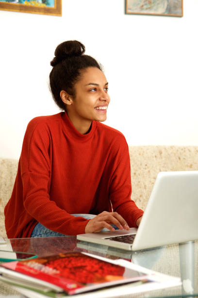 istock Young woman sitting at table with laptop 868441630