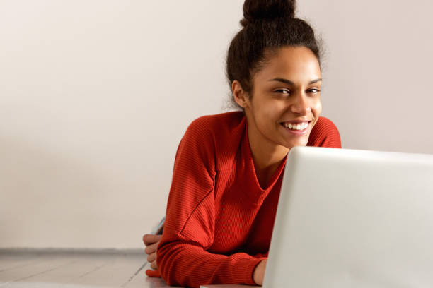 istock Young woman lying on floor and smiling with laptop 868441962
