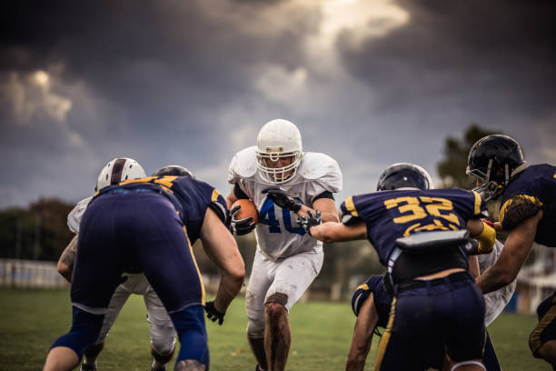 istock Determined American football player making an effort while passing through defense players. 868445922