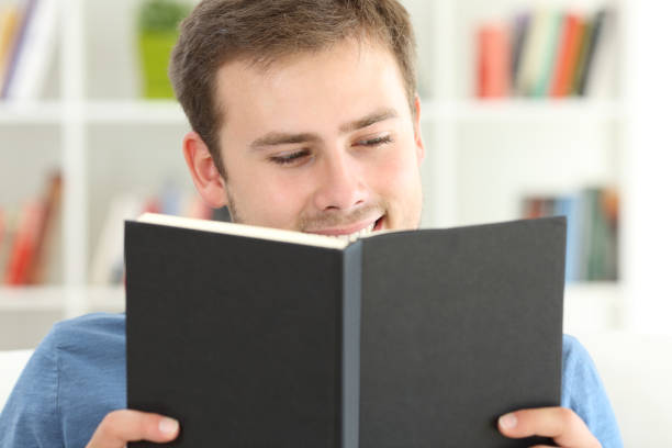 istock Front view of a man reading a book at home 868447716