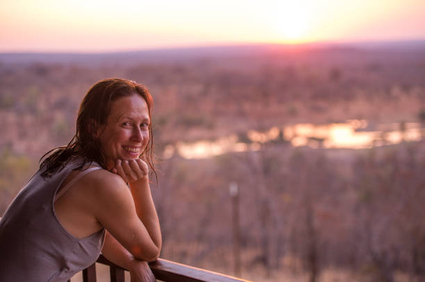 istock Woman overlooking waterhole at sunset looking at camera 868450350