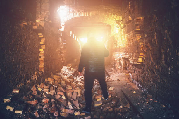 istock Man in abandoned underground ruined tunnel, light from end or exit from brick creepy corridor, industrial broken mine 868450934