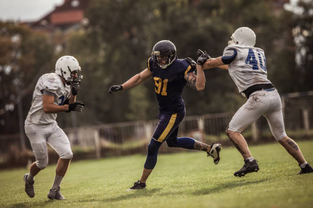 tentando evitar seus oponentes em um jogo de jogador de futebol americano. - football player group of people running american football - fotografias e filmes do acervo