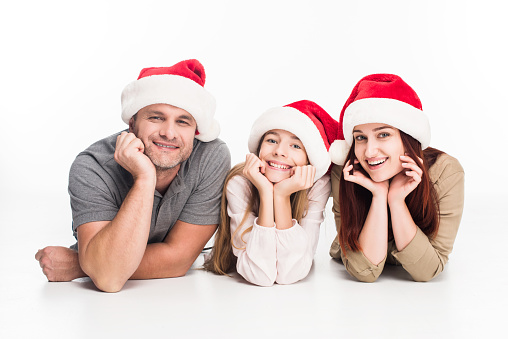 young smiling family in santa hats, isolated on white