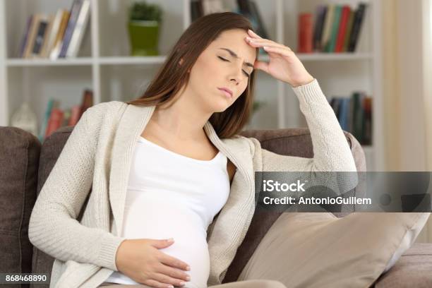 Pregnant Woman Suffering Migraine At Home Stock Photo - Download Image Now - Pregnant, Confusion, Women