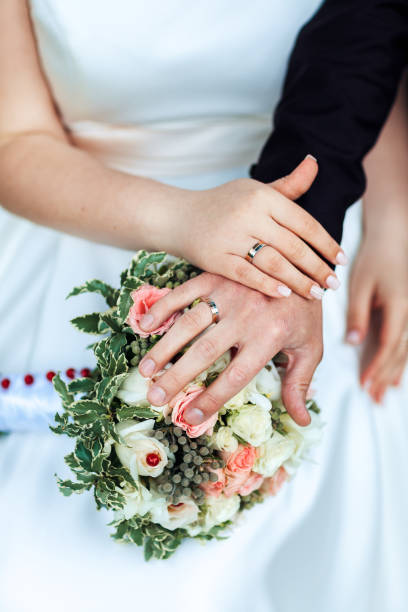 istock Bride hands with ring and wedding bouquet of flowers 868470164