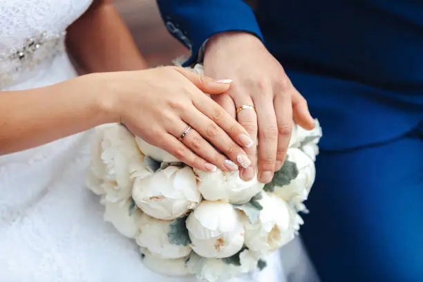 Photo of Bride hands with ring and wedding bouquet of flowers
