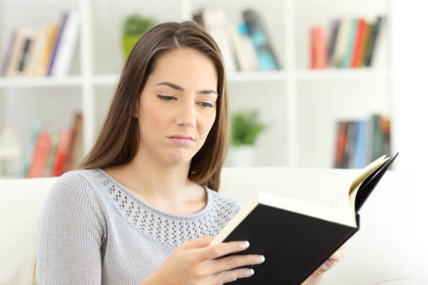 istock Bored woman reading a bad book 868473164