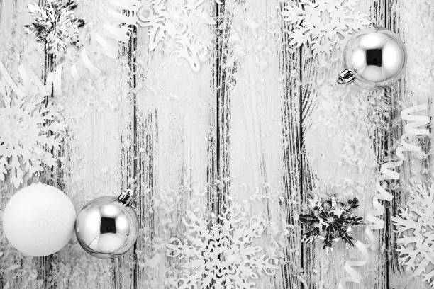 istock New year theme: Christmas tree white and silver decorations, balls, snow, snowflakes, serpentine on white retro stylized wood background black and white 868473206