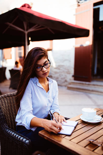 istock Young businesswoman with glasses making notes in diary 868481450