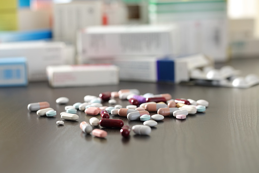 Close up of a lot of pills and medicines on a black wooden table