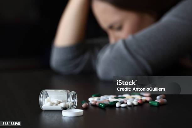 Depressed Woman Beside A Lot Of Pills Stock Photo - Download Image Now - Medicine, Addiction, Depression - Sadness