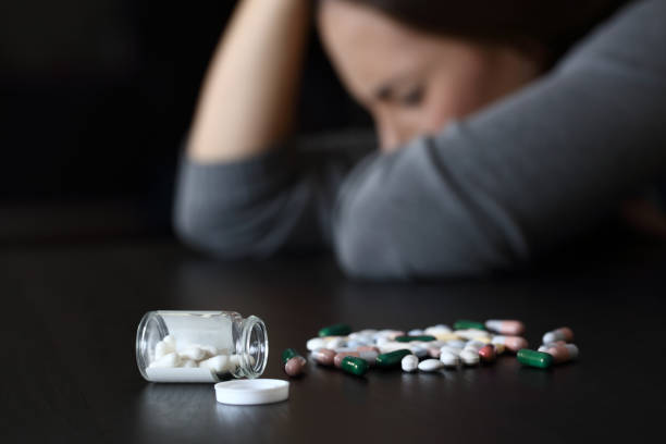 mulher deprimida ao lado de um monte de pílulas - drug awareness - fotografias e filmes do acervo