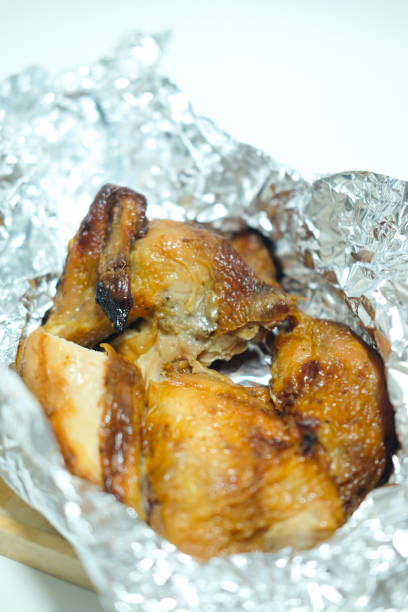 istock Baked chicken smoked on an aluminum foil on white background 868490884