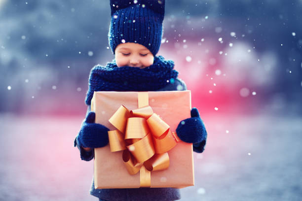 urocze dziecko z dużym pudełkiem na prezent pod opadami śniegu. skoncentruj się na pudełku prezentowym - christmas child gift holiday zdjęcia i obrazy z banku zdjęć