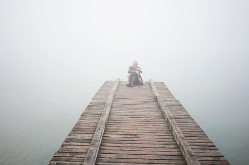 Woman at wooden deck at foggy winter day