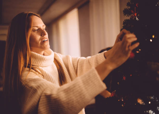 istock Mature redhead woman decorating Christmas tree at home 868495976