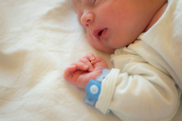 New Life Newborn baby boy sleeping in his crib. baby bracelet stock pictures, royalty-free photos & images