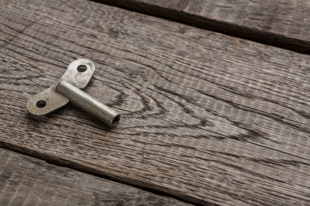 A high-resolution macro of a vintage key fully visible on wood, with its gripping part highlighted in red. Ideal for historical, security, and design-oriented concepts.