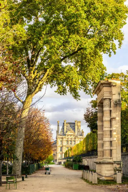 Photo of View of the Tuileries garden in Paris at the end of an autumn day with a remnant arcade of the Tuileries palace in the foreground and the Flore pavilion of the Louvre palace in the background