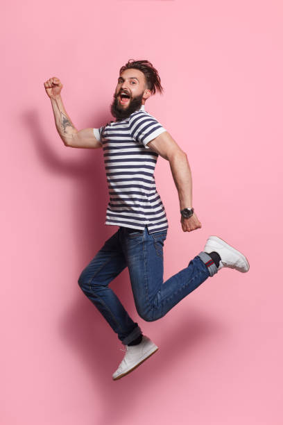 istock Excited man posing in jump on pink 868523074