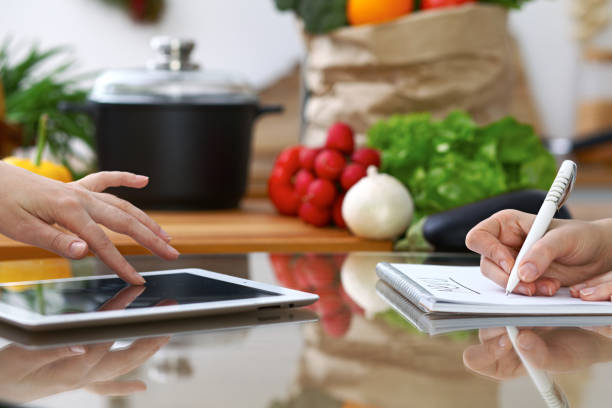 istock Close-up of  human hands are gesticulate over a tablet in the kitchen. Friends having fun while choosing menu or making online shopping 868526162