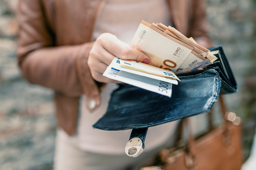 Mujer sosteniendo en cartera de las manos con dinero del euro. Chica de ciudad es sacar dinero de la cartera photo