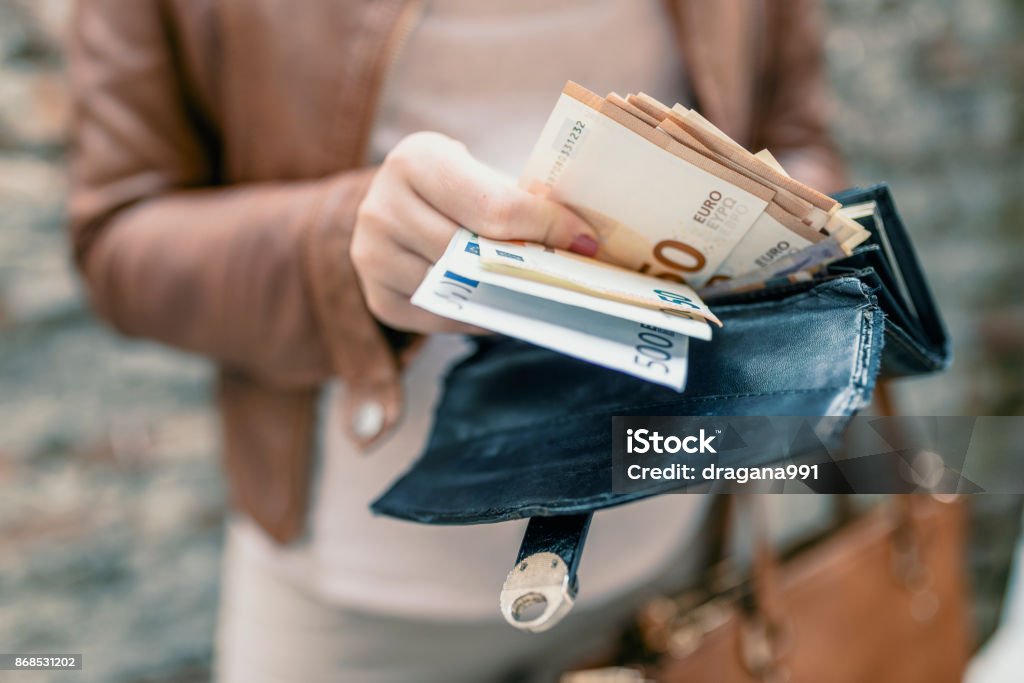 Woman holding in hands wallet with euro money. City girl is taking out money from wallet European Union Currency Stock Photo