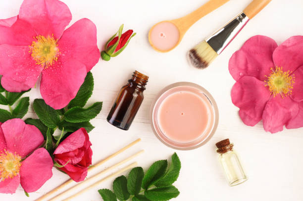 Pink fresh wild rose flowers and leaves, bottles and jars, top view. Herbal extracts preparation natural cosmetic products. botanical spa treatment stock pictures, royalty-free photos & images
