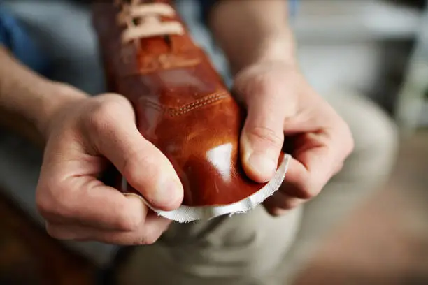 Modern cobbler stretching new leather all over boot model