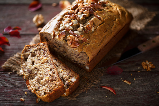 Banana bread with nuts on wood background