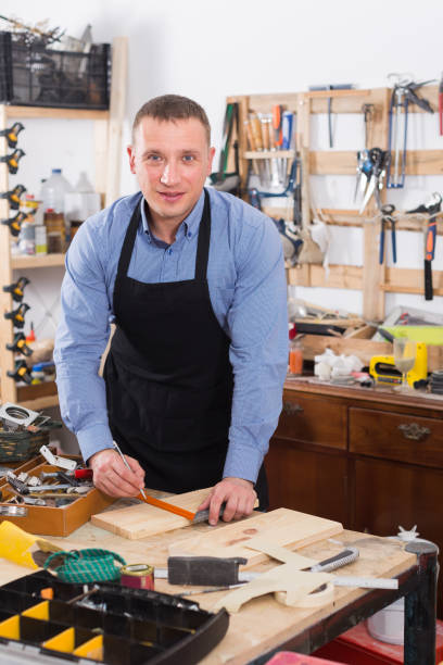 istock woodwork studio with shelving holding pieces of wood, with a carpenter standing in his workbench 868568986