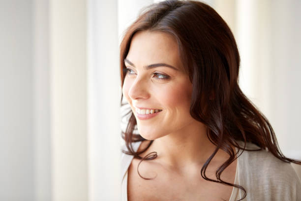 istock happy young woman looking through window at home 868576906