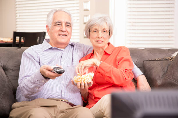 couple adulte âgé à la maison regarder la télévision ensemble. - senior adult comfortable relaxation latin american and hispanic ethnicity photos et images de collection