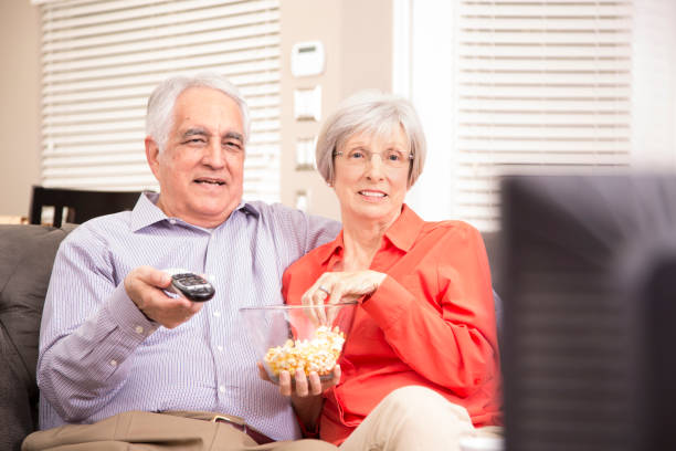 couple adulte âgé à la maison regarder la télévision ensemble. - senior adult comfortable relaxation latin american and hispanic ethnicity photos et images de collection