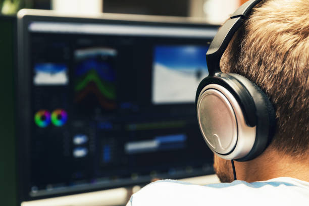 man doing video editing on computer with headphones on man doing video editing on computer with headphones on post production house stock pictures, royalty-free photos & images