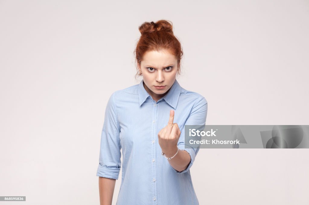 Bad emotions. Fuck sign. Redhead bussiness woman. Bad emotions. Fuck sign. Redhead bussiness woman. Isolated on gray backgraund , studio shot Actor Stock Photo