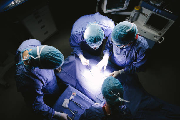 equipo de cirujanos realizar la cirugía en sala de operaciones - performance surgery doctor men fotografías e imágenes de stock