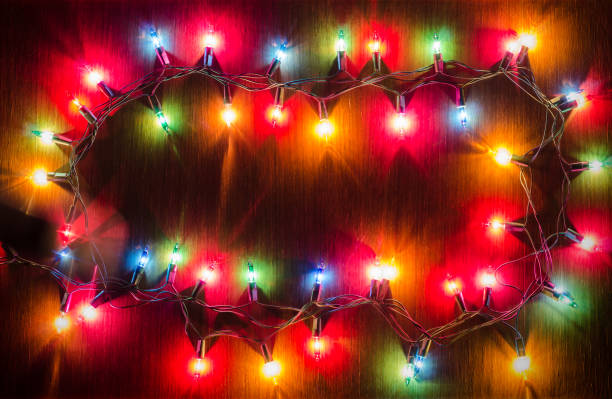 istock Christmas light bulbs were turned on or lid on string in multi colours; blue, yellow, red, pink, orange and green on dark teakwood background at night time, Xmas holiday decoration ornament concept 868608738