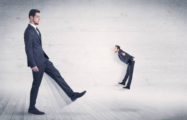 istock Big man kicking small man with grungy background 868609102